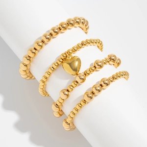 Close-up of four-piece gold beaded bracelet set with heart charm on display