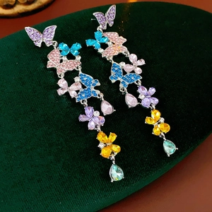 Macro detail of colorful crystal butterfly drop earrings on luxury velvet base