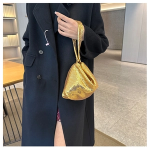 Gros plan d'un sac de soirée en paillettes dorées tenu par un mannequin élégant
