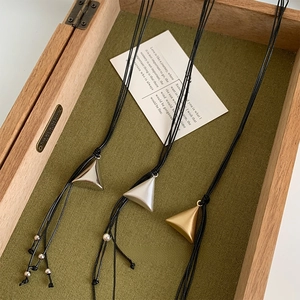 Detailed close-up of geometric pyramid necklaces in gold and silver on velvet lining