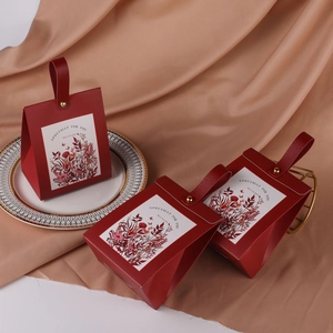 Detail of burgundy floral wedding favor box with red leather handle and gold foil text