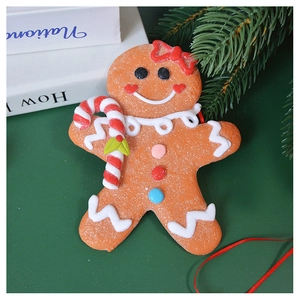 Close-up of a gingerbread man ornament with candy cane and red bow on a green background