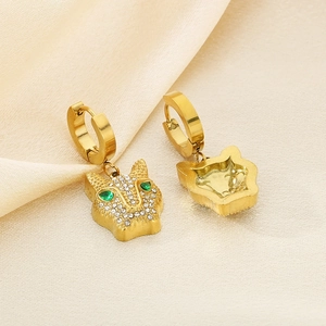 Detailed view of gold leopard earrings with clear crystals and green gemstone eyes