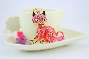 Close-up of golden cat pendant with pink rhinestones for keychains or bags