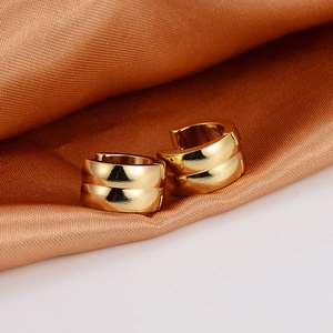 Close-up of gold stainless steel hoop earrings on elegant bronze silk fabric