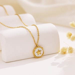 Detailed close-up of a gold star pendant with white enamel on a white arch pedestal