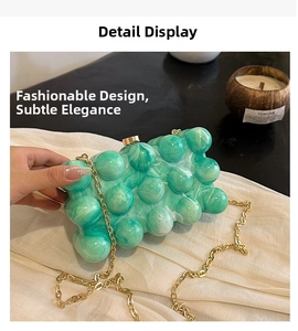 Détail d'une pochette en acrylique vert avec texture bulle et chaîne dorée marbrée