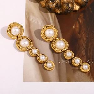 Détail macro de boucles d'oreilles longues dorées 18 carats avec cinq perles blanches