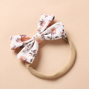 Close-up of floral bow baby headband with pink roses on soft nylon elastic band