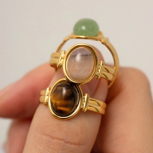 Macro shot of three gold-plated oval gemstone rings stacked on a model's finger