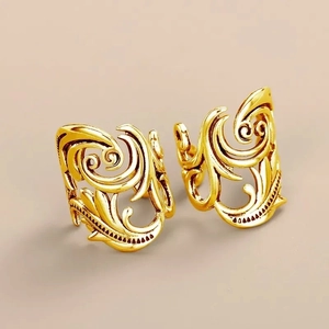 Detail of vintage golden leaf ear cuffs with intricate baroque floral textures