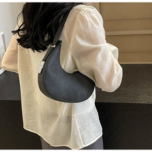 Close-up of black crescent shoulder bag with silver hardware and wide leather strap