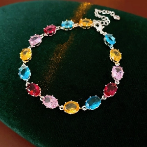 Macro detail of oval colorful zircon stones in four-prong silver settings on a velvet mat