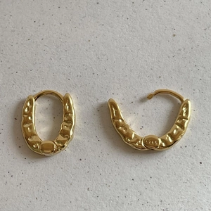 Macro shot of 925 sterling silver gold earrings with irregular lava hammered texture