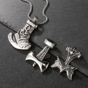 Viking Mjölnir and wolf head steel pendants with Nordic knotwork on slate background