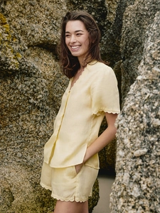 Détail des bords festonnés sur l'ensemble chemise et short en lin jaune clair