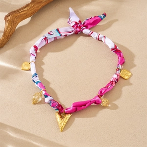 Detail of pink floral fabric necklace with golden heart and geometric metal pendants