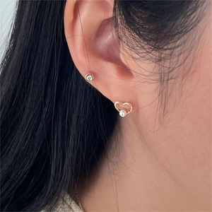 Close-up of heart pearl earrings and round zircon studs set on model's ear