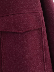 Dettaglio ravvicinato del cappotto di lana bordeaux con tasca ampia e cuciture rifinite