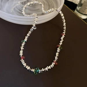 Détail d'un collier en perles argentées irrégulières avec des pierres colorées en gouttes