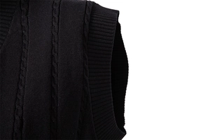 Detail der schwarzen Zopfstrickweste mit feiner Textur und geripptem Armausschnitt