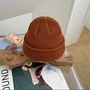 Close-up of caramel knitted beanie with detailed texture on rustic wooden branch
