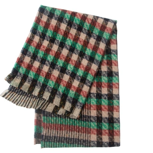 Detail view of the green and red classic plaid scarf with natural frayed edges and soft texture