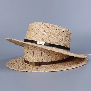 Close-up of stacked raffia sun hats featuring leather bands and metallic detail