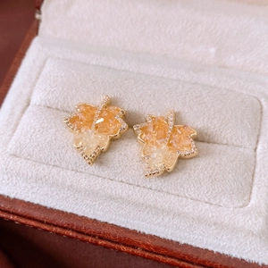 Macro detail of gold maple leaf earrings with amber crystals and zircon on velvet pad
