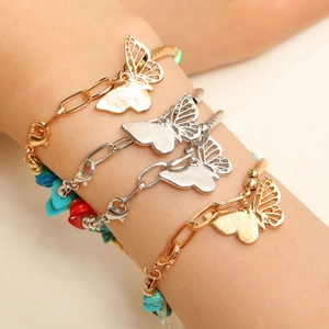 Gros plan de bracelets papillon bohèmes superposés avec chaîne dorée et pierres colorées
