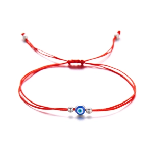 Detailed view of handmade red braided evil eye bracelet with blue bead and silver accents