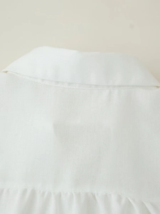 Detail view of the white linen shirt collar and textured fabric with subtle pleats