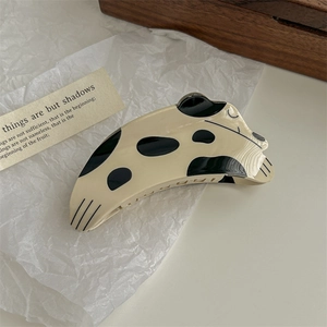 Close-up of a speckled cream and black acetate hair claw clip on white crinkled paper