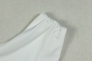 Detailed macro view of the elastic gathered waistband and fine stitching on a white dress