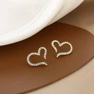 Macro detail of elegant gold heart earrings with shimmering zircon pavé on silk