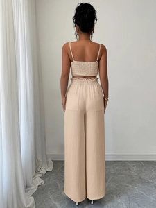 Dettaglio del tessuto beige increspato sul top con schiena scoperta e pantaloni larghi a vita alta