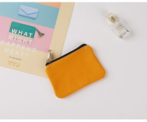 Detail of yellow canvas coin purse with zipper closure on a clean decorative background