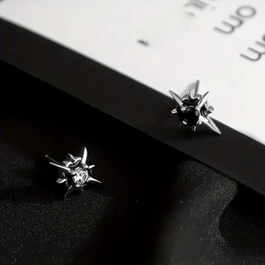 Detail view of silver star stud earrings with black and white zircon stone inlays