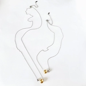 Detail of minimalist mixed metal gold and silver bead pendants on fine steel chain