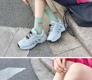 Detail of light gray mesh sports sneakers with lace-up design and green crew socks