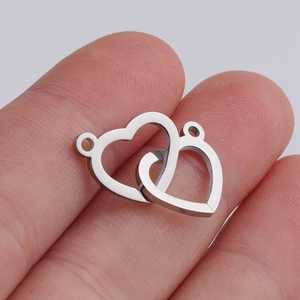 Close-up of interlocking silver heart connectors held on finger for DIY jewelry making