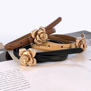Three slim leather belts in black, brown, and beige with golden rose-shaped metal buckles