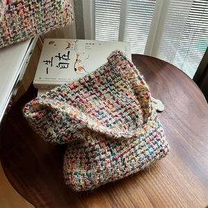 Detail of colorful knitted shoulder bag showing thick yarn texture and woven flap pattern