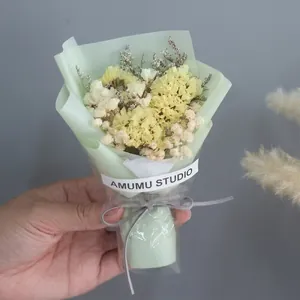 Detailed close-up of mini dried rose bouquet in green wrap held in hand for gift decor