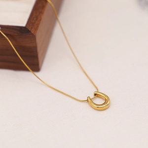 Detail of a gold U-shaped horseshoe pendant on a fine snake chain necklace