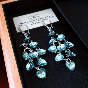Detailed shot of blue heart crystal tassel earrings in a black velvet jewelry box