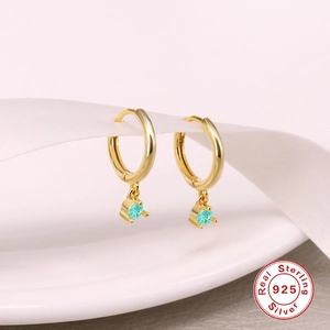 Detail of S925 sterling silver hoop earrings with round turquoise pendant on white ribbon
