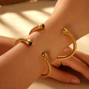 Twisted cable cuff bracelet in gold finish with blue and brown gemstone terminals