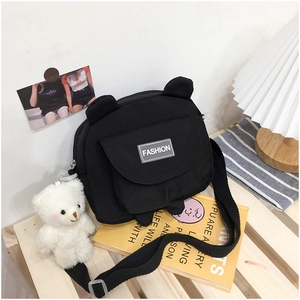 Close-up of black canvas bear crossbody bag with cute white bear pendant and fashion tag