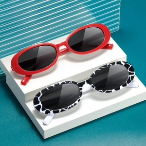 Vintage oval sunglasses in bright red and cow print on a modern display stand